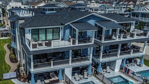 Une maison à plusieurs étages dotée d’un grand balcon, d’un espace salon extérieur et d’une piscine.