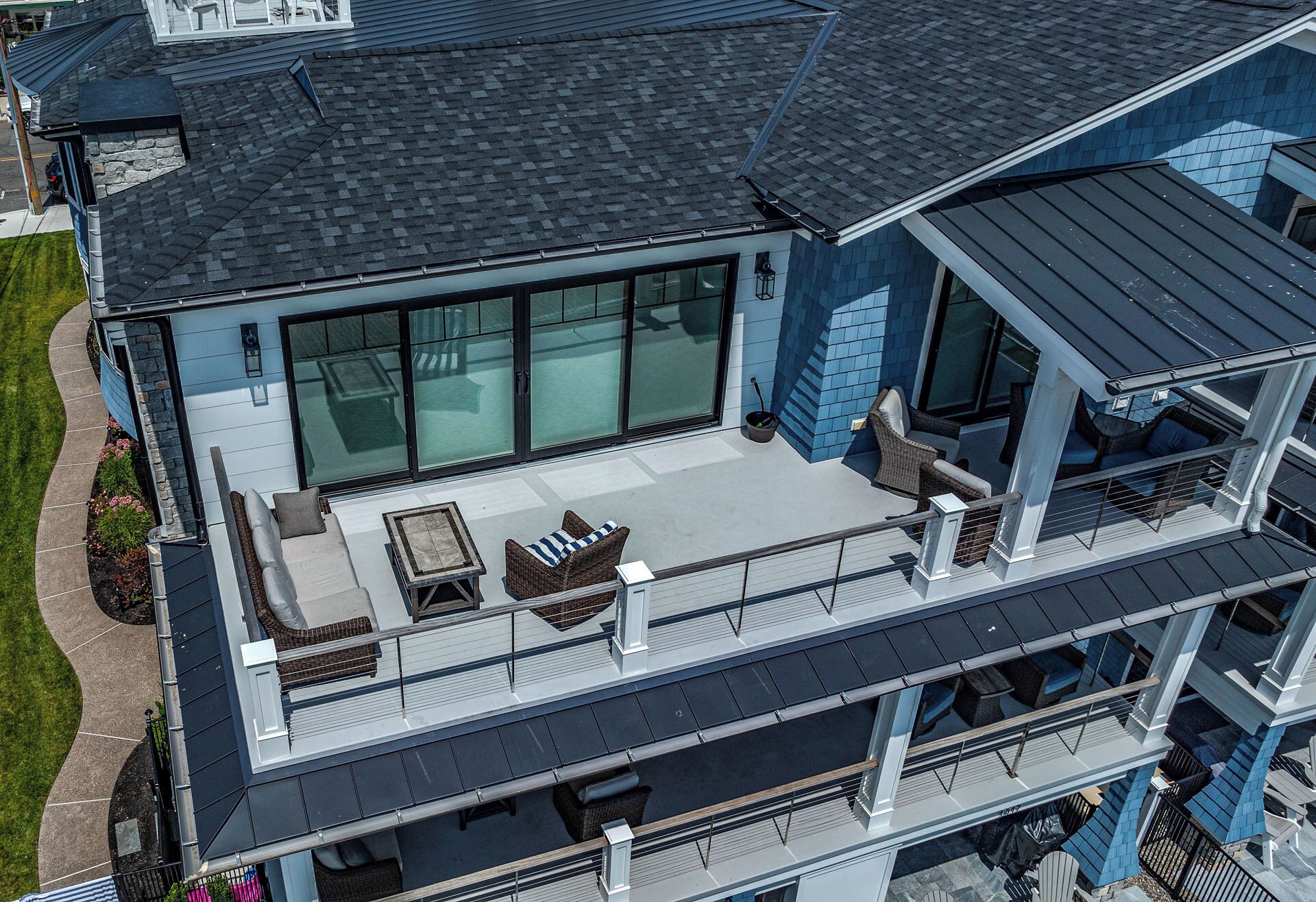 Un immeuble à plusieurs étages doté d’un balcon aménagé avec des sièges d’extérieur et d’une grande fenêtre.