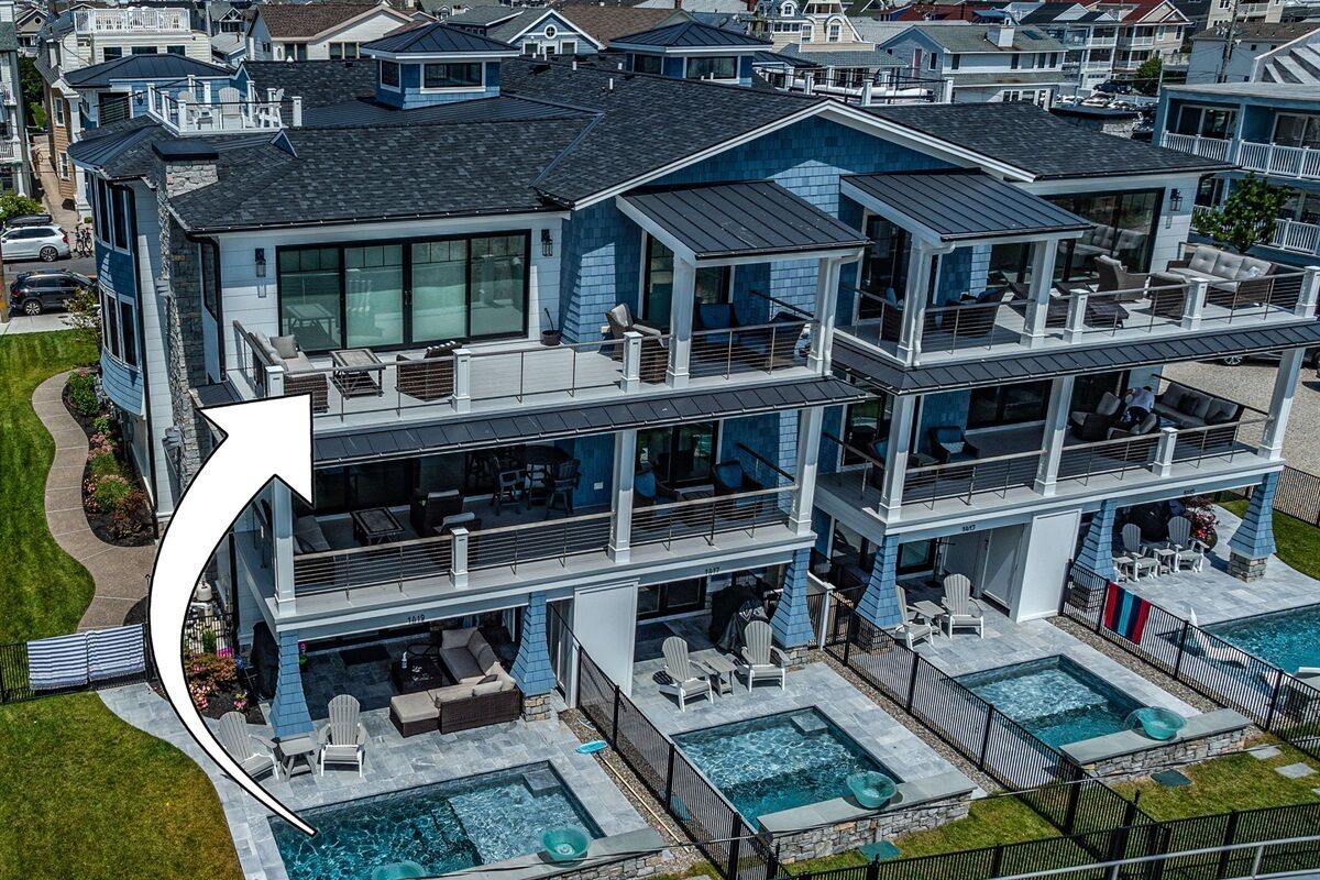 Une maison moderne à plusieurs étages, dotée d’un grand jardin comprenant une piscine et un espace salon extérieur.