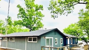 Uma casa térrea com varanda frontal, um pequeno deck e uma garagem.