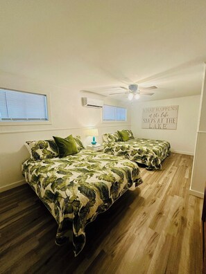 A bedroom with two beds, a ceiling fan, and a wall sign.