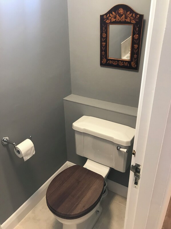 A bathroom with a toilet, a toilet paper holder, and a mirror with a floral frame. - Tranquility, In grounds of Dower house on large country estate in the Candover's (Basingstoke)