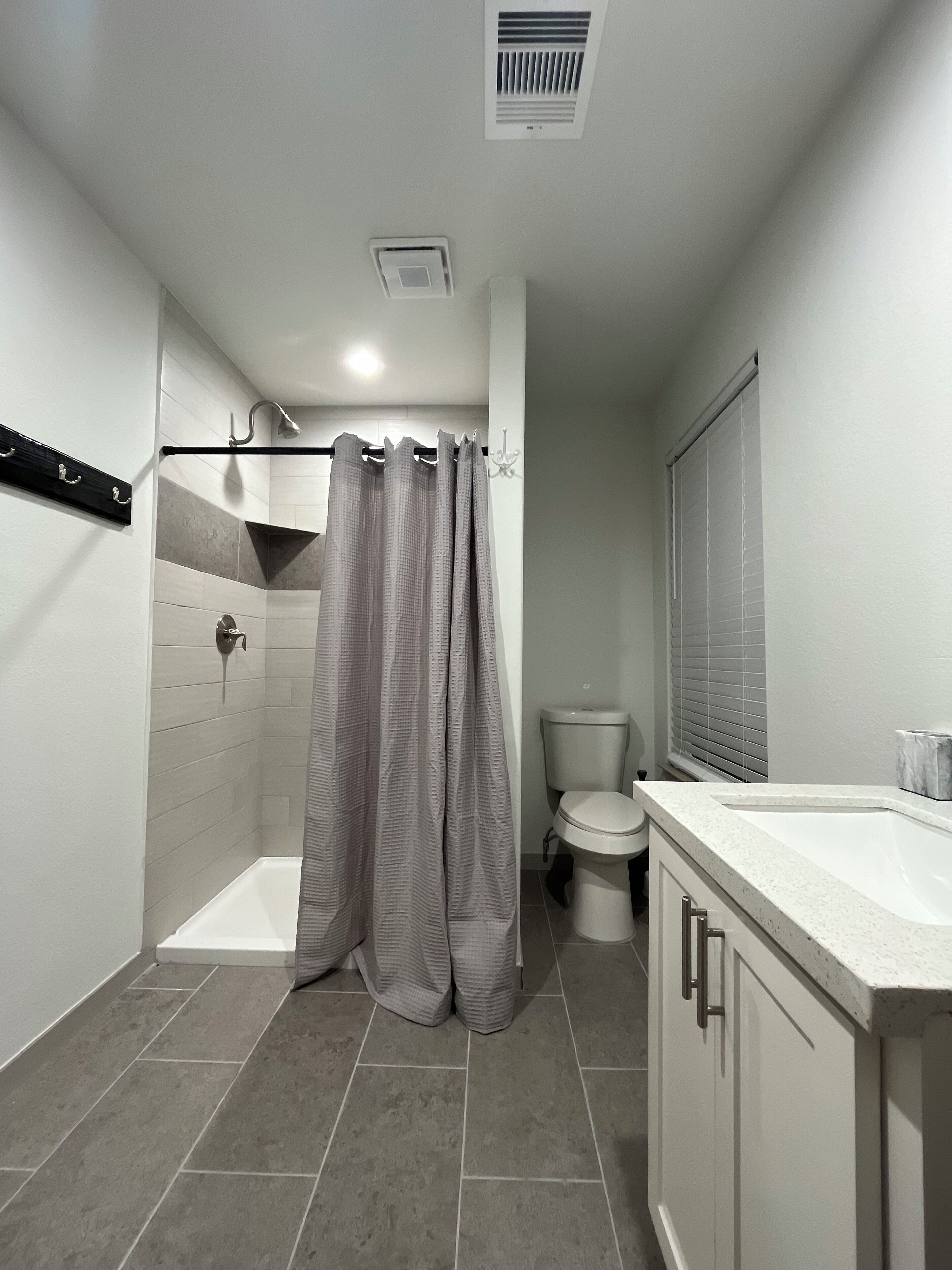 A bathroom with a shower, toilet, and sink.