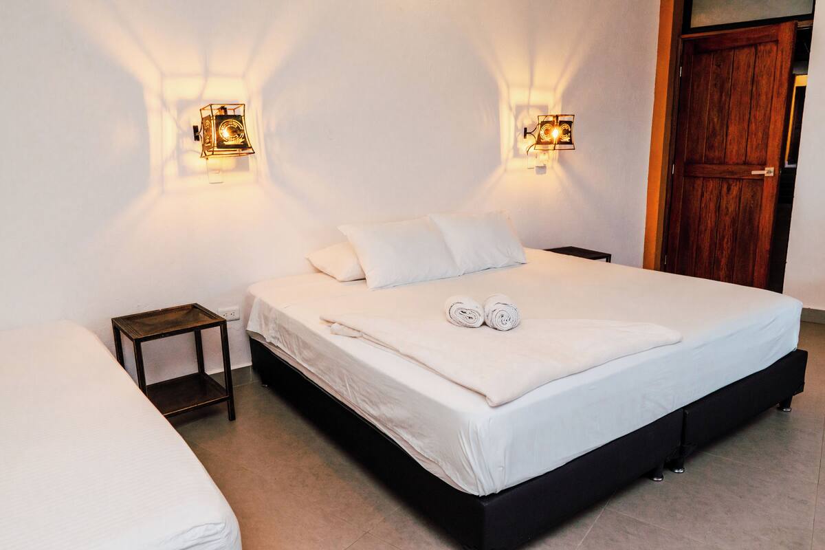 A bedroom with a large bed, two bedside tables, and two wall-mounted light fixtures.