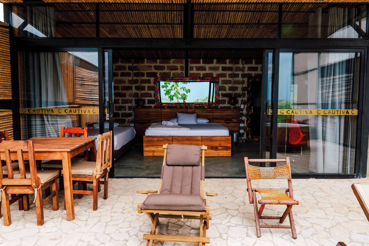 A room with a bed, a TV, a wooden table, and chairs.