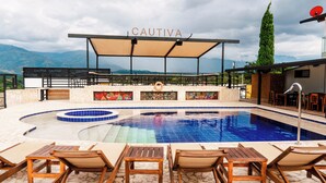 Ein Poolbereich mit Liegestühlen und einer überdachten Sitzgelegenheit, mit 'CAUTIVA'-Beschilderung.