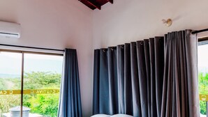 Ein Schlafzimmer mit einem großen Bett, einem Deckenventilator und Blick ins Grüne.