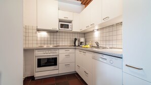 A compact kitchen with white cabinets, a microwave, a Bosch dishwasher, and a tiled backsplash.