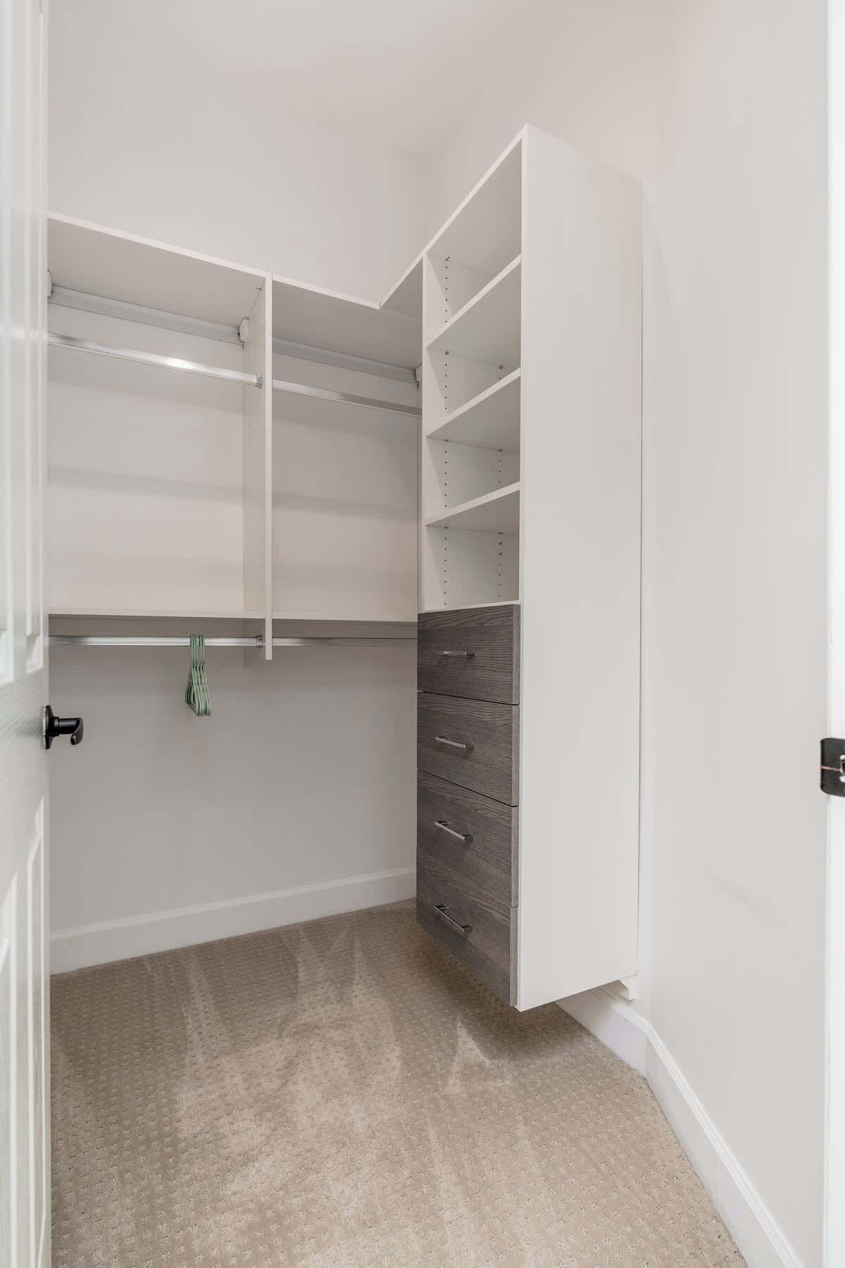 A walk-in closet with open shelving, a hanging rod, and a set of drawers.