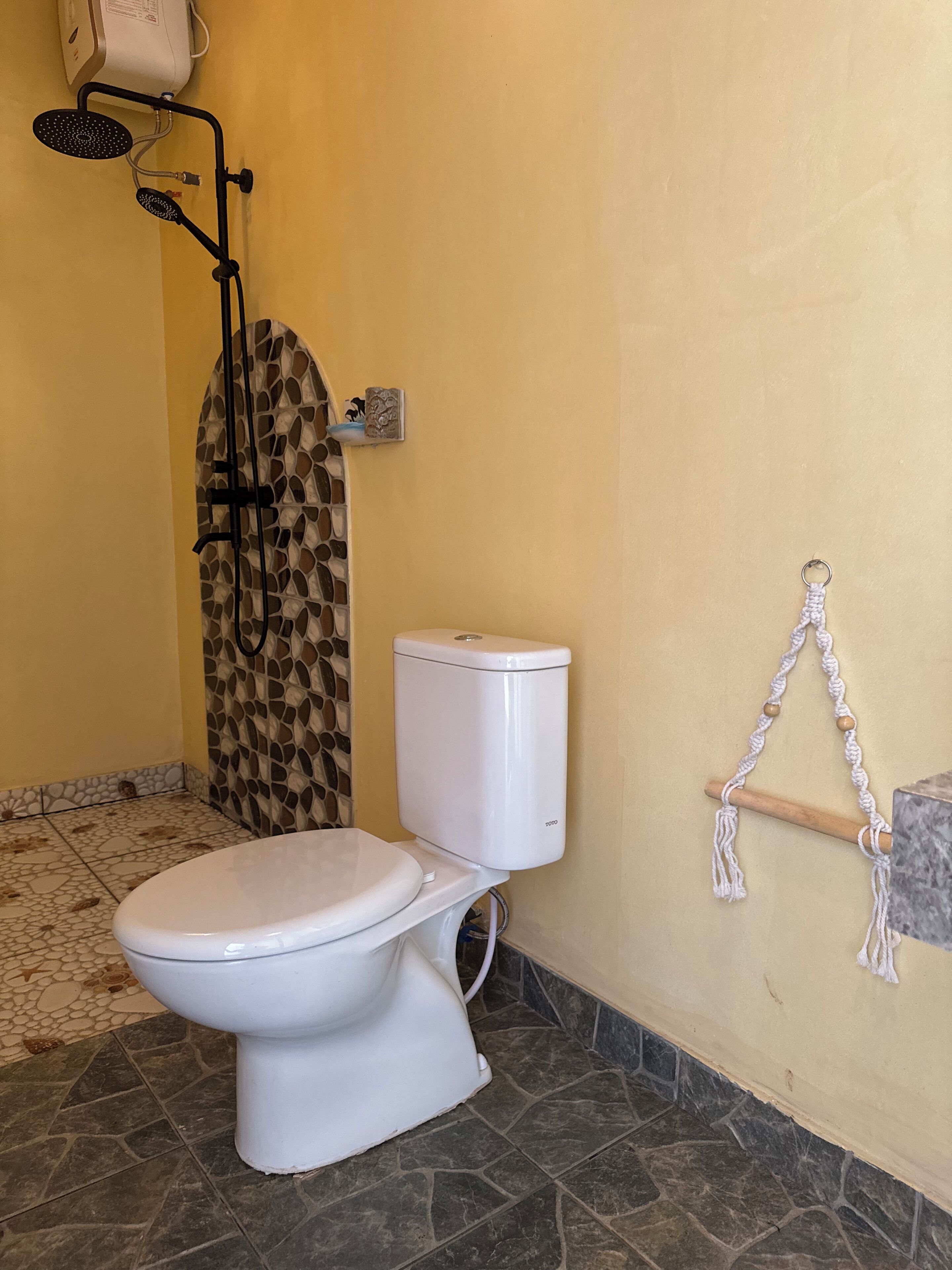 Une salle de bain avec des toilettes, une douche et un mur décoré de mosaïques.
