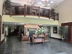 Eine geräumige Lobby mit Kamin, Ledersitzmöbeln und einer Treppe zu einer oberen Ebene.
