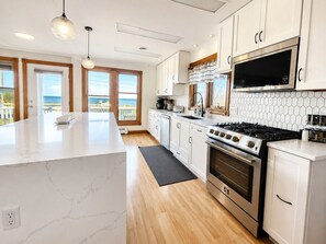 A modern kitchen with a large island, stainless steel appliances, and a view to the outside. - Castleview Cove- 5Bd 4Ba Lakefront Luxury Retreat! (Port Sanilac)