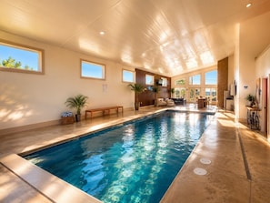An indoor swimming pool with clear water, wooden deck, and seating area with tables and chairs. - Castleview Cove- 5Bd 4Ba Lakefront Luxury Retreat! (Port Sanilac)