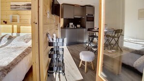 Une pièce de taille modeste comprenant un lit, un coin cuisine et un petit espace repas.