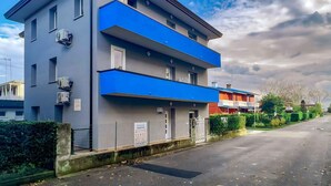 En bygning med flere etager, grå facade og blå detaljer, med aircondition og et skilt, der angiver ledige lejligheder.