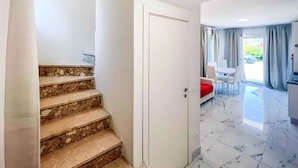 Un interior moderno con una escalera que lleva a un comedor y cocina.