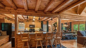 Interior de una cabaña de madera con cocina, comedor y sala de estar.