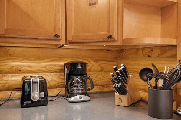 A kitchen with wooden cabinets, a toaster, a coffee maker, and a utensil holder.