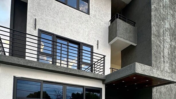 A modern building with a large window, a balcony, and a concrete facade. - Cozy hotel in enjoyable Kingston with AC, WiFi (Kingston)