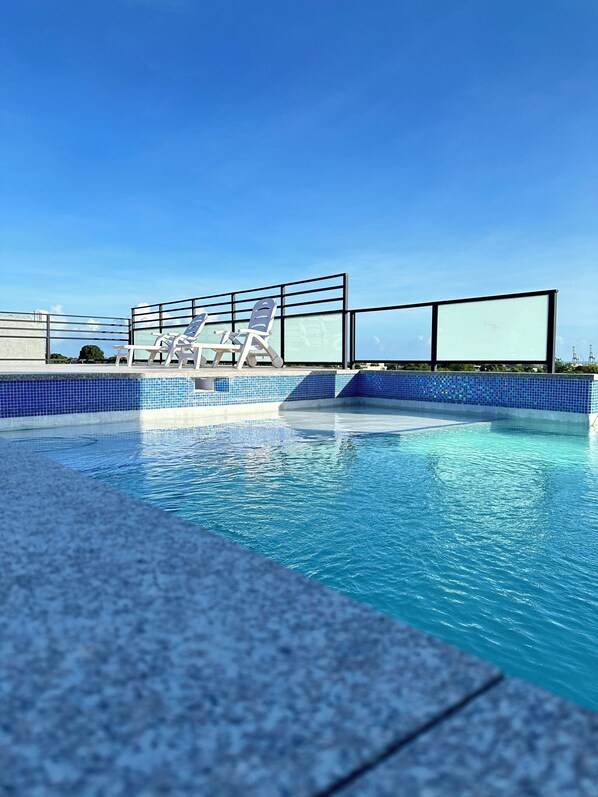 Una piscina con agua cristalina azul, rodeada por un bordeado de baldosas.