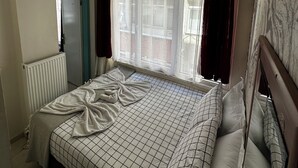 A bedroom with a large bed, a radiator, a window with curtains, and a ceiling light fixture. - Diva Otel (Isparta)