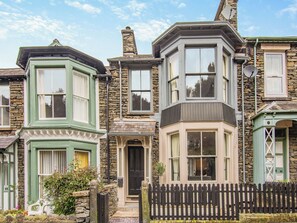 A row of traditional terraced houses with stone facades, bay windows, and a picket fence.
