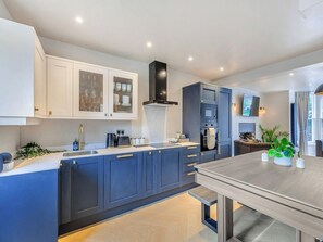 Une cuisine moderne avec des meubles de couleur bleu foncé, un plan de travail blanc et un four encastré.