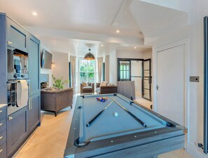 Un salon moderne avec une table de billard, un canapé et un téléviseur.