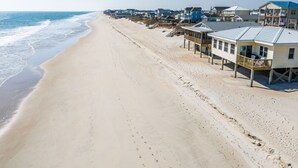 Propiedad frente a la playa con varias construcciones, incluyendo una casa con balcón y una estructura independiente con terraza.