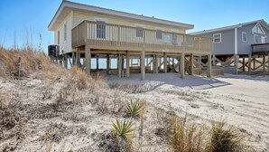 Una casa frente a la playa con balcón y terraza cubierta.