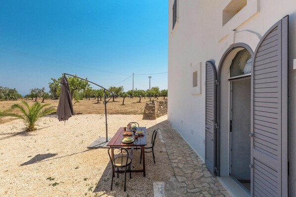 Mesa al aire libre con vista a un viñedo y un edificio con ventanas arqueadas.