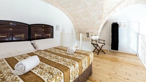 A bedroom with a large bed, a wooden floor, and a stone ceiling.