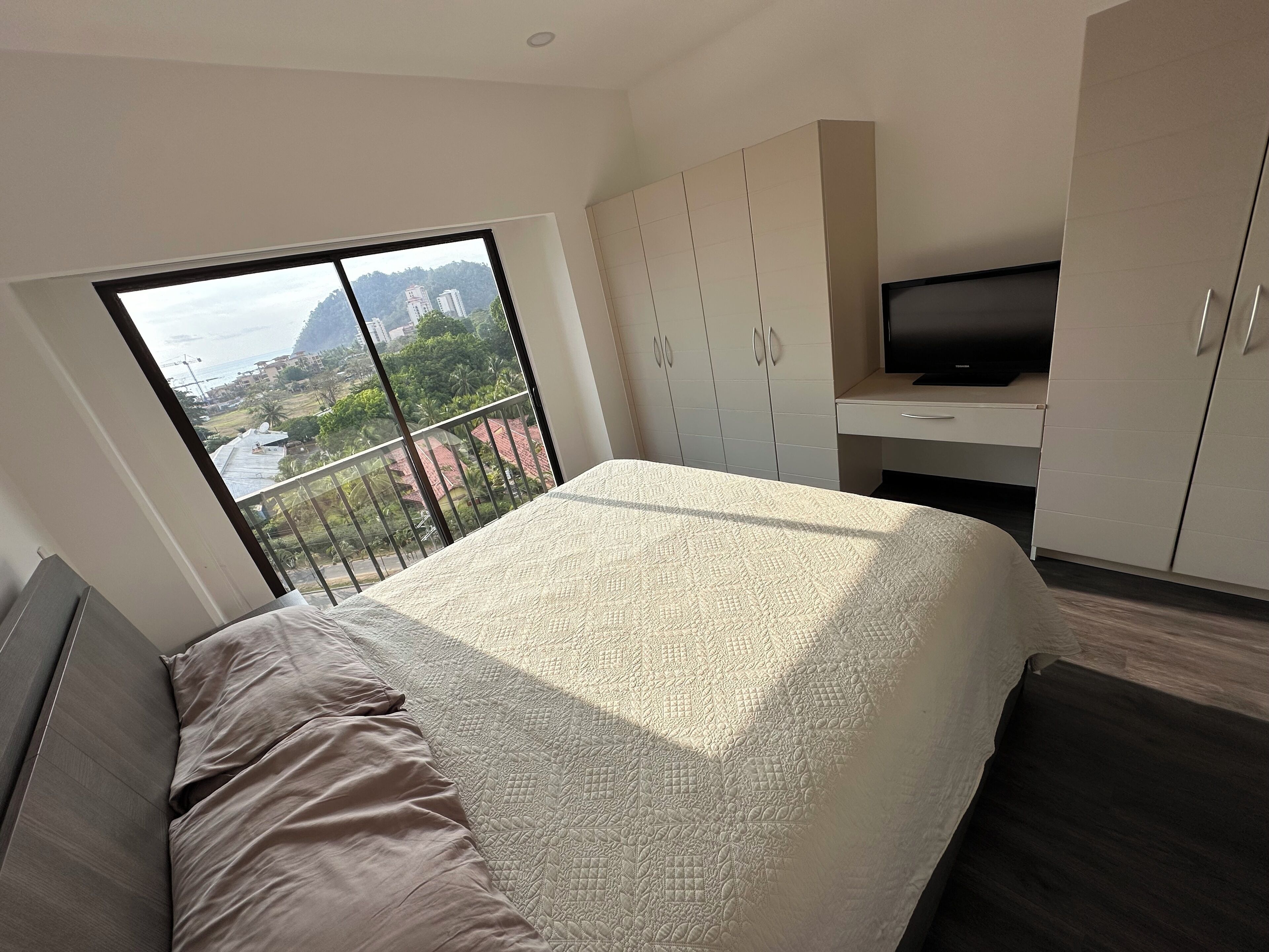 Una camera da letto moderna con un letto grande, una TV e un armadio.