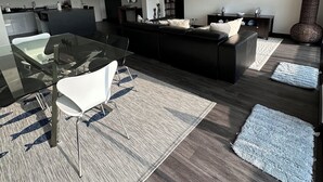 Un salon moderne avec une table à manger en verre, un canapé noir et un téléviseur à écran plat.