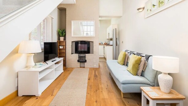 Una sala de estar moderna con sofá, televisión, chimenea y una escalera que sube a otro nivel.
