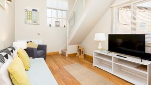 Una sala de estar moderna con sofá, televisor y piso de madera.