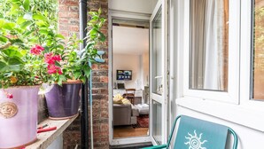 A small balcony with potted plants, a teal chair, and a view into a living room. - Peaceful, zen apartment with parking, Kew, London - Pass the Keys (Richmond)