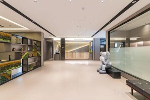 Un moderno vestíbulo de hotel con mostrador de recepción, zona de estar y pared de vidrio.