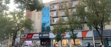 A multi-story building with a modern facade, featuring a prominent blue section and signage for a 5G service provider.