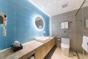 A modern bathroom with a blue tiled wall, a round mirror, a sink, and a toilet. - Homeinn · neo (Fuzhou Wanxiang New City Tianmu Square) (Fuzhou)