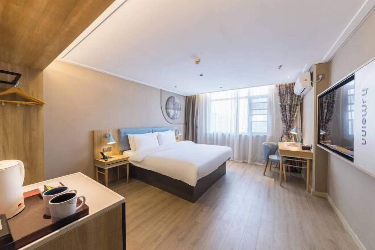 A modern hotel room with a large bed, bedside tables, a desk, and a TV.