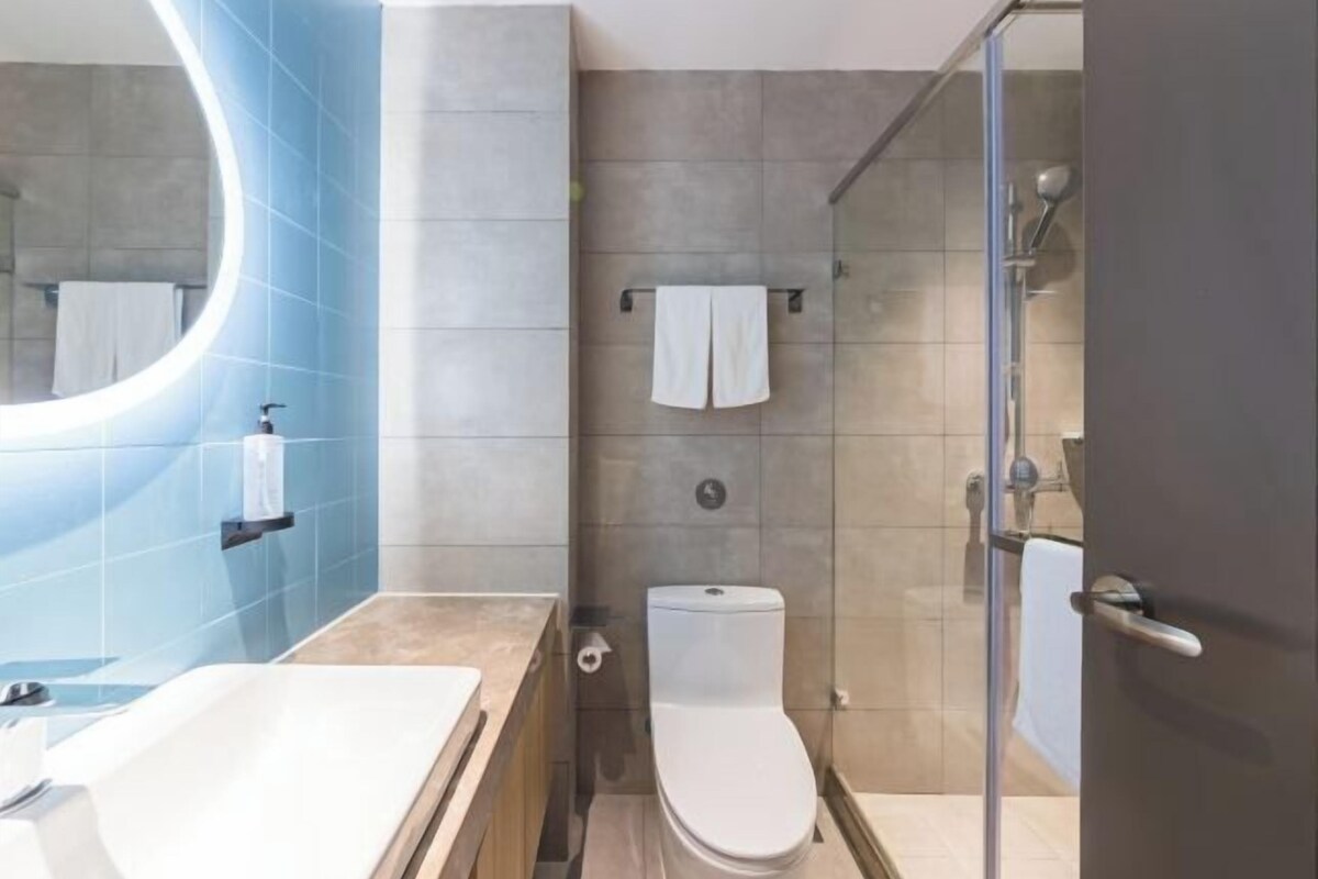 A modern bathroom with a bathtub, toilet, and glass shower enclosure.