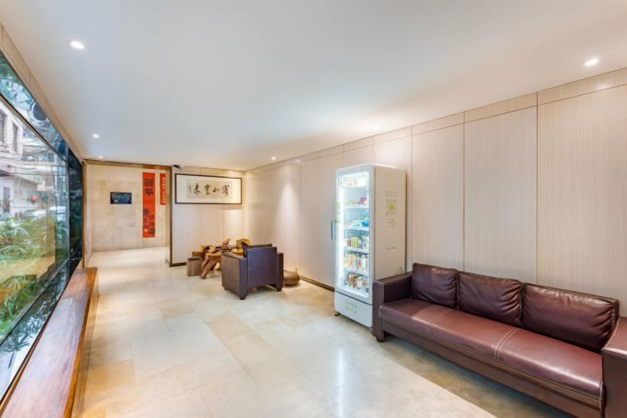 Vestíbulo de hotel con mostrador de recepción, área de descanso y máquina expendedora.