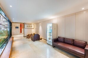 A hotel lobby with a reception desk, seating area, and a vending machine.