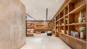 Un hall d’entrée moderne avec un comptoir d’accueil en bois, un espace salon et des étagères ornées d’objets décoratifs.