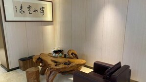 Une table basse en bois au design original, un canapé en cuir et un panneau décoratif encadré accroché au mur.