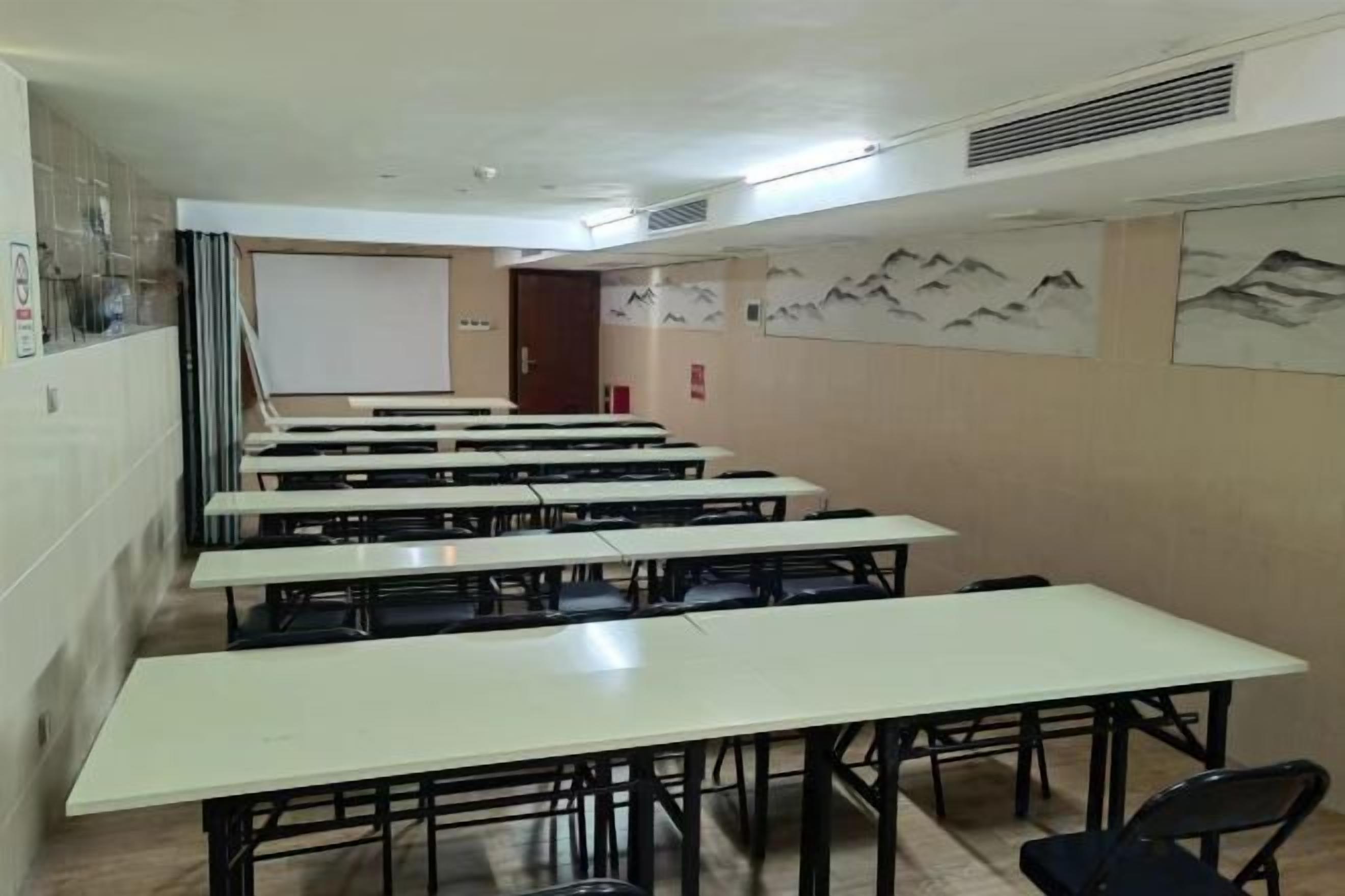 Un aula con varias mesas y sillas, una pizarra y carteles educativos en las paredes.