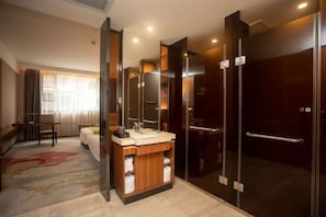 A modern hotel room with a large mirror, a wooden vanity, a shower enclosure, and a bed with a floral rug. - Elong Yam Hotel (Near Panyu Chimelong and Guangzhou South Railway Station) (Guangzhou)