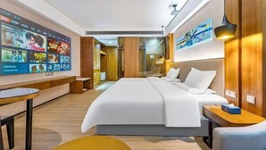 Une chambre d’hôtel moderne dotée d’un grand lit, d’un téléviseur fixé au mur, d’un bureau et d’un coin salon.