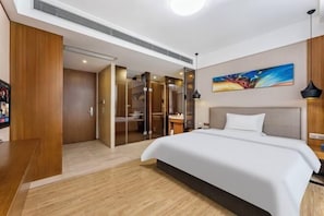 Una habitación de hotel moderna con una cama grande, un cuadro en la pared y un escritorio de madera.